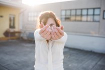 Portrait of young woman with hands reaching out on sunlit roof terrace — Stock Photo