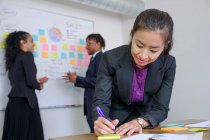 Businessman and businesswomen, in office, brainstorming, sticking notes to whiteboard — Stock Photo