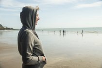 Вид сбоку женщины в капюшоне на пляже — стоковое фото