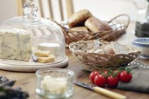Tavolo con pane fresco, formaggi e pomodori di vite — Foto stock