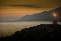 Faro sobre rocas iluminadas por la noche, Camogli, Liguria, Italia, Europa - foto de stock