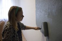 Giovane donna che applica vernice grigia con rullo a parete a casa — Foto stock