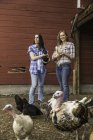 Retrato de una joven y su hermana sosteniendo un pollo y un pato en el rancho, Bridger, Montana, EE.UU. - foto de stock