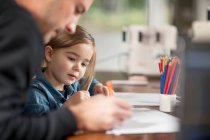 Junger Mann und seine Tochter zeichnen am Tisch — Stockfoto