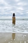 Mujer joven en vadeadores de pesca en el mar - foto de stock