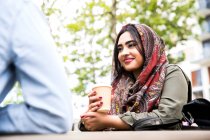 Mulher vestindo hijab desfrutando de café com amigo — Fotografia de Stock