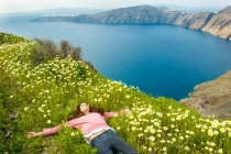 Mädchen legt sich auf Blumenfeld, Santorini, Kikladhes, Griechenland — Stockfoto