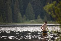 Vista lejana de la pesca del muchacho adolescente usando la red - foto de stock