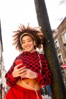 Ritratto di giovane donna in cuffia che tiene lo smartphone all'aperto — Foto stock