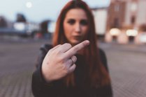 Woman showing middle finger to camera — Stock Photo
