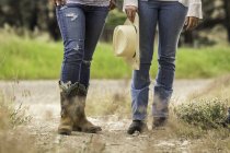 Taille nach unten Blick auf zwei junge Frauen, die auf einem Feldweg in Ranch, Bridger, Montana, USA stehen — Stockfoto