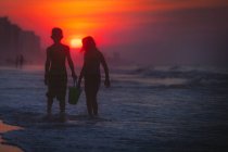 Irmãos remando no mar ao pôr do sol, North Myrtle Beach, Carolina do Sul, Estados Unidos — Fotografia de Stock