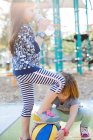 Petite sœur essayant de récupérer le basket sous le pied d'une fille — Photo de stock