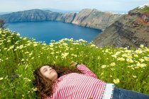 Девочка лежит на цветочном поле, Санторини, Кикладес, Греция — стоковое фото