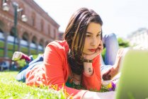 Woman on city break using laptop on grass, Milan, Italy — Stock Photo