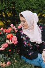 Молода жінка в хіджабі дивиться на троянди — стокове фото