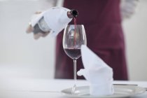 Garçom no restaurante derramando copo de vinho tinto, seção meio — Fotografia de Stock