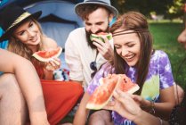 Jóvenes amigos adultos boho comiendo rodajas de melón en el festival - foto de stock