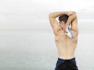 Vista posteriore di uomo petto nudo che tende le braccia vicino all'acqua, Melbourne, Victoria, Australia, Oceania — Foto stock
