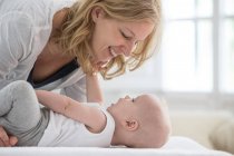 Baby boy lying on bed face to face with mother — Stock Photo