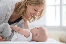 Bébé garçon couché sur le lit face à face avec la mère — Photo de stock