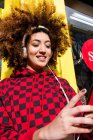 Retrato de mujer joven al aire libre con auriculares que sostienen el teléfono inteligente - foto de stock