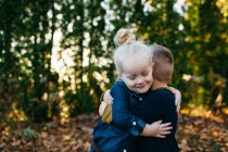 Cute female toddler hugging twin brother in autumn garden — Stock Photo