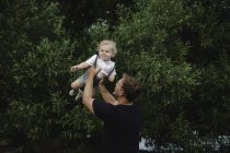 Mature man lifting up toddler son — Stock Photo
