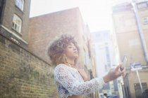 Низький кут зору Молода жінка бере селфі на смартфон — стокове фото