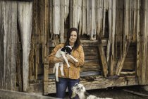 Mature woman on farm, holding young goat — Stock Photo