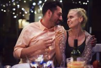 Paar sitzt am Tisch, hält Weingläser in der Hand, lächelt — Stockfoto