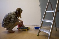 Mujer joven preparando pintura gris para la pared interior en casa - foto de stock