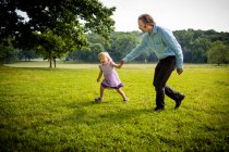 Menina correndo no campo rural com o pai — Fotografia de Stock