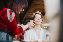 Bride preparing for wedding with make up artist — Stock Photo