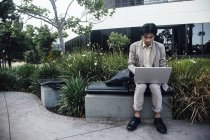 Junger Mann sitzt im Freien und benutzt Laptop — Stockfoto