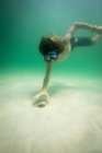 Подводный вид на мальчика-подростка в плавательной маске на дне моря — стоковое фото