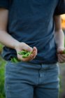 Young boy on farm, holding freshly picked sugar snap peas, mid section — Stock Photo