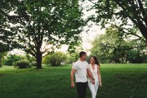 Романтическая молодая пара, прогуливающаяся в парке, держась за руки — стоковое фото