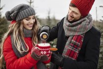 Junges Paar gießt Kaffee beim Weihnachtsbaumkauf aus Wald ein — Stockfoto