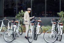Giovane uomo che si prepara a utilizzare biciclette a noleggio — Foto stock