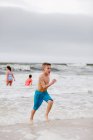 Хлопчик біжить по краю води на пляжі, острів Дофін, Алабама, США. — стокове фото