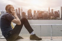 Businessman sitting on waterfront and making smartphone call — Stock Photo