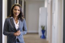 Portrait of businesswoman in office hallway smiling at camera — Stock Photo