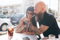Mature hipster couple lighting cigarette at sidewalk cafe, Valencia, Spain — Stock Photo