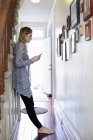 Frau benutzt Handy im Hausflur — Stockfoto