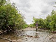 Man walking on river with fishing rod, Clark Fork, Montana — Stock Photo