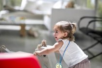 Baby girl with rocking horse — Stock Photo