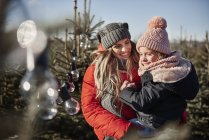 Chica y madre mirando las luces del árbol de navidad del bosque - foto de stock