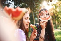 Les jeunes femmes boho faisant visage souriant avec tranche de melon au festival — Photo de stock