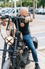 Mature male hipster astride motorcycle, looking over his shoulder — Stock Photo